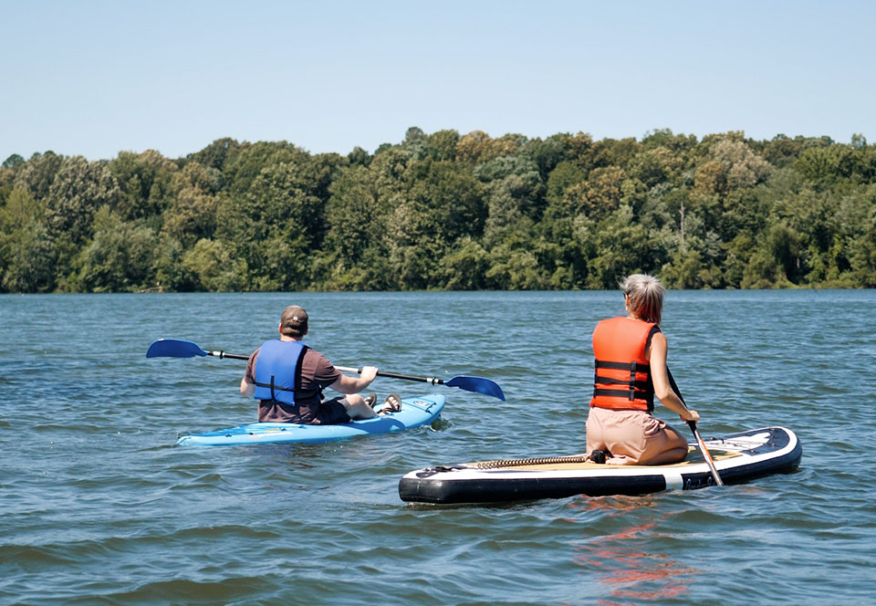 Kayaker and paddle boarder on water